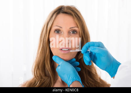 Femme mature qui reçoivent l'injection cosmétique sur la lèvre en clinique Banque D'Images