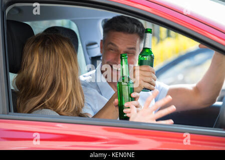 Close-up of happy young couple enjoying beer à l'intérieur de la voiture Banque D'Images