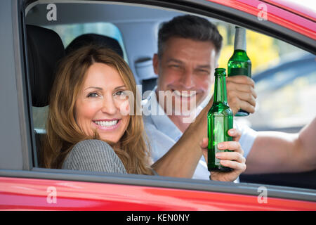 Close-up of happy young couple enjoying beer à l'intérieur de la voiture Banque D'Images
