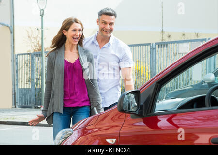 Heureux couple standing in front of new car Banque D'Images