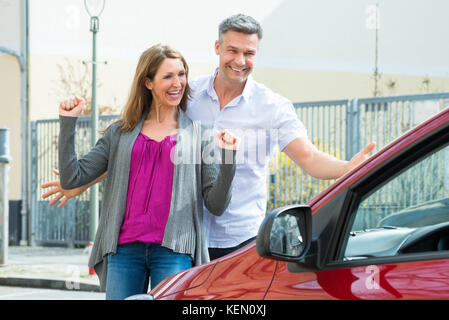 Heureux couple standing in front of new car Banque D'Images