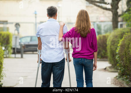 Vue arrière de la femme avec son mari handicapé debout sur Street Banque D'Images