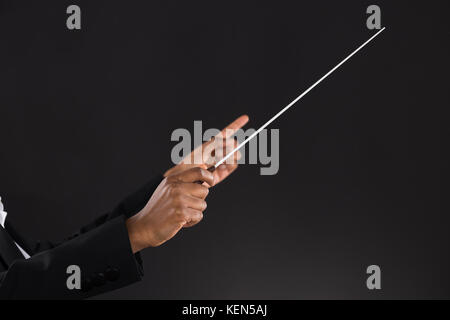 Close-up de femmes chef d'orchestre holding baton sur fond noir Banque D'Images