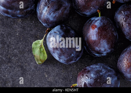 Les prunes mûres récoltées fraîches sur fond sombre Banque D'Images