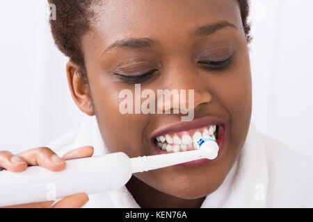 Close-up of a Young African Woman se brosser les dents avec une brosse électrique Banque D'Images