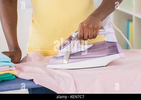 Close-up of Woman Ironing Clothes sur table à repasser Banque D'Images