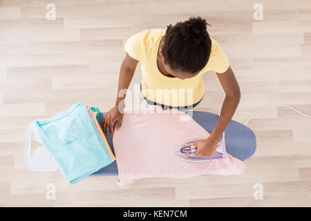 High Angle View of African Woman Ironing Clothes sur table à repasser Banque D'Images