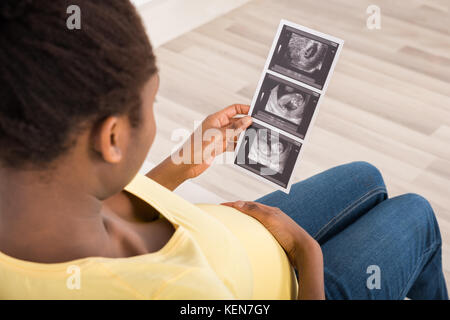 Close-up of pregnant woman Sitting on Sofa Looking At Échographie Banque D'Images