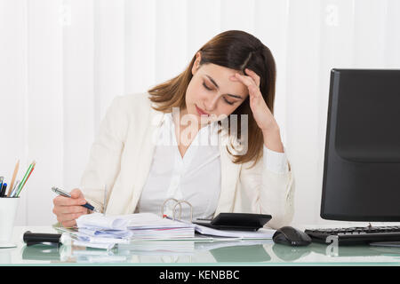 Jeune femme déprimée calcul facture in office Banque D'Images