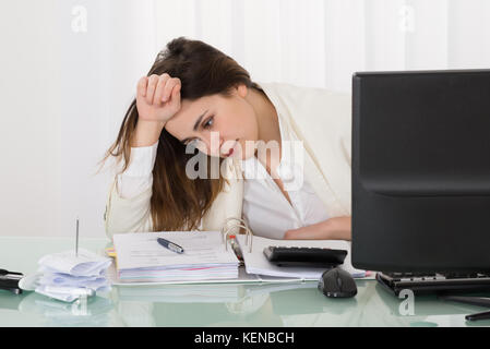 Souligné businesswoman sitting in office with hand on head Banque D'Images