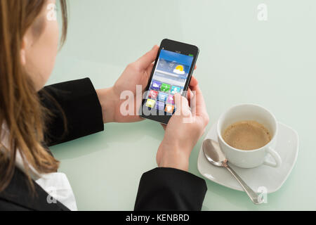 Close up of businesswoman contrôle météo on smartphone in office Banque D'Images