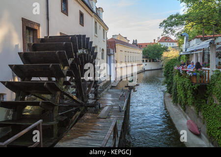 Peu de gens de manger dans un petit restaurant idyllique et par la roue du moulin de l'eau du canal et sur l'île Kampa, à Prague, en République tchèque, à l'été. Banque D'Images