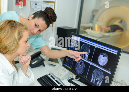 Deux techniciens médicaux pointant à l'IRM du patient Banque D'Images