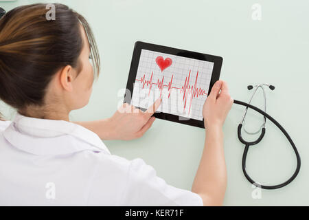 Close-up of young female cardiologue analyse pulsation sur tablette numérique Banque D'Images