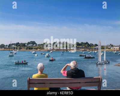 MORBIHAN Sentier de la Plage, couple assis observant diverses activités de navigation de plaisance voile Golfe du Morbihan, Larmor-Baden, Morbihan, Bretagne, France Banque D'Images