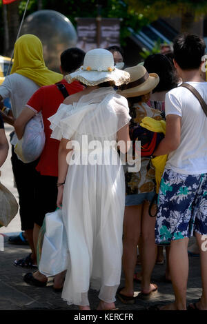 Tourisme chinois. Comité permanent de la foule. Femme dans une robe de mousseline blanche. Pleine longueur. Odd one out Banque D'Images