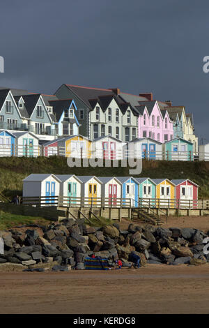 Maisons très colorées et huttes de plage contre un ciel sombre et couvant noir ou gris à Bude dans le nord de Cornwall sur la plage au bord de la mer au-dessus des rochers Banque D'Images