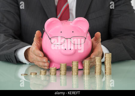 Close-up of businessman hand couvrant tirelire laughing at desk Banque D'Images