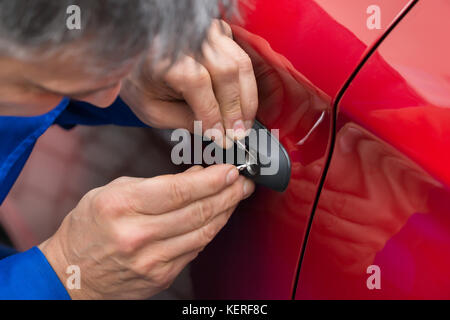 Close-up of hand holding personne lockpicker pour ouvrir la porte de voiture Banque D'Images