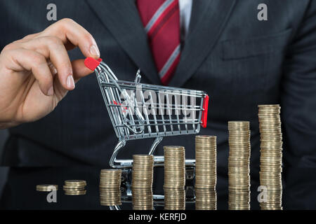 Close-up of Businessman avec pile de pièces et les petits Panier à 24 Banque D'Images