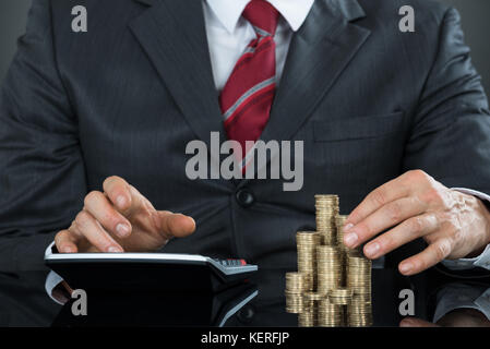 Close-up of a Businessman part compter des pièces Using Calculator Banque D'Images