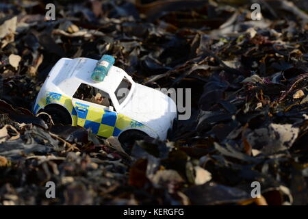 Jouet en plastique jetés- voiture de police flics sur l'épaule douce d'algues sur la ligne de marée haute Banque D'Images