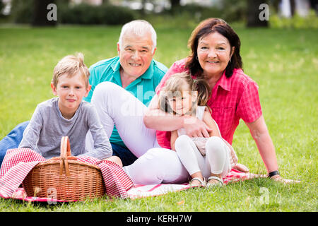 Happy parents assis avec les enfants dans le parc Having Picnic Banque D'Images