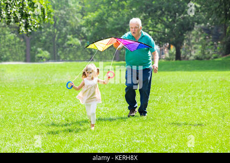 Heureux Grand-père aider Kid à voler en Kite Park Banque D'Images