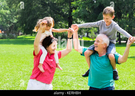 Heureux grands-parents âgés : Profitez de Piggyback Ride avec les enfants ensemble dans Park Banque D'Images