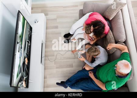 Les enfants jouant à la télévision jeu vidéo de voiture avec la famille à la maison Banque D'Images