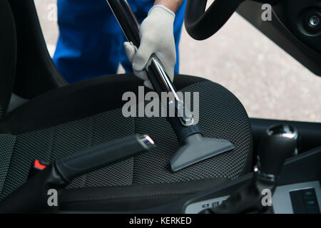 Nettoyage de la saleté et la poussière de la place dans la voiture, un employé avec un aspirateur sur le lavage de voiture Banque D'Images