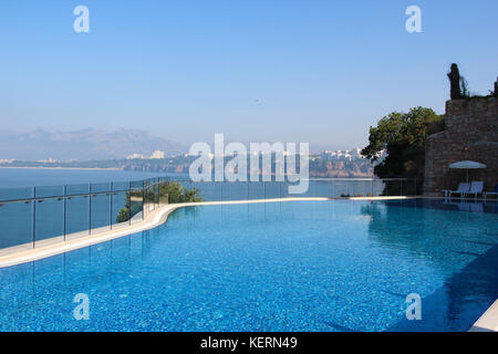 Une vue sur la piscine et la mer turquoise avec de l'eau claire avec une chaîne de montagnes à l'horizon et la ligne de la côte méditerranéenne avec le resort Banque D'Images