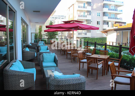 Vue sur le café vide avec une terrasse, des canapés avec des coussins, des chaises en bois, vert d'arbustes et de parasols. dans la rue dans la méditerranée resort Banque D'Images