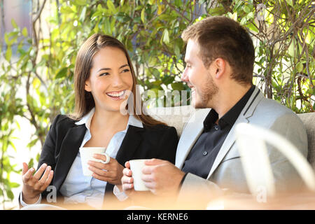 Deux dirigeants heureux de parler à une pause-café assis dans un bar terrasse Banque D'Images