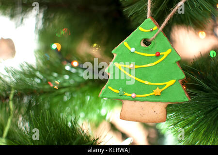 Cookie dans la forme d'un arbre de Noël est suspendu à une branche d'arbre de Noël. selective focus, l'arrière-plan flou. maison de vacances ou de l'image. Banque D'Images