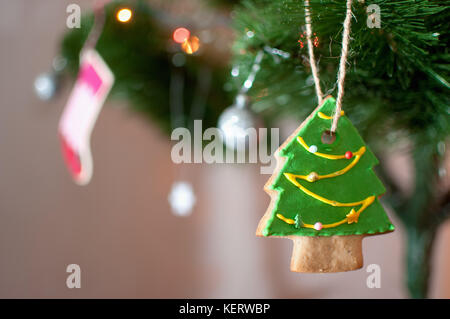 Cookie dans la forme d'un arbre de Noël est suspendu à une branche d'arbre de Noël. selective focus, l'arrière-plan flou. maison de vacances ou de l'image. Banque D'Images