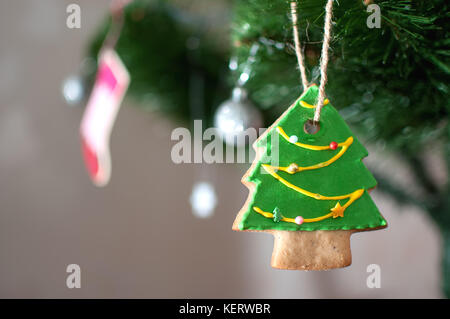 Cookie dans la forme d'un arbre de Noël est suspendu à une branche d'arbre de Noël. selective focus, l'arrière-plan flou. maison de vacances ou de l'image. Banque D'Images