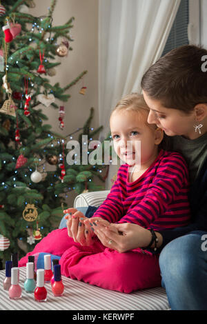 Mère et fille s'amusant peinture ongles le jour de Noël Banque D'Images