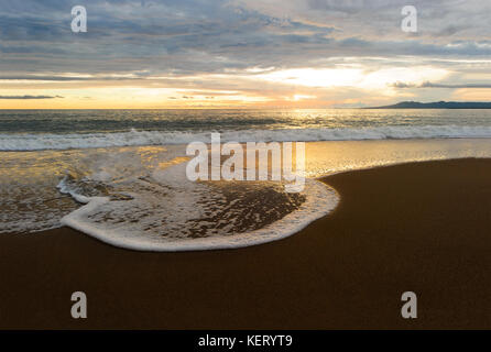 Coucher Soleil océan est un paisible paysage pittoresque sur la plage avec le soleil sur l'horizon de l'océan comme une vague douce jusqu'au rivage. Banque D'Images