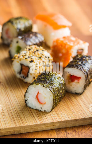 Rouleaux de sushi japonais sur planche à découper en bois. Banque D'Images