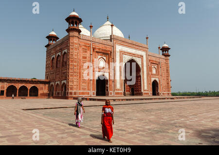 Femme en rouge la marche en face de la mosquée flanquant le Taj Mahal, l'Inde, Uttar Pradesh Banque D'Images