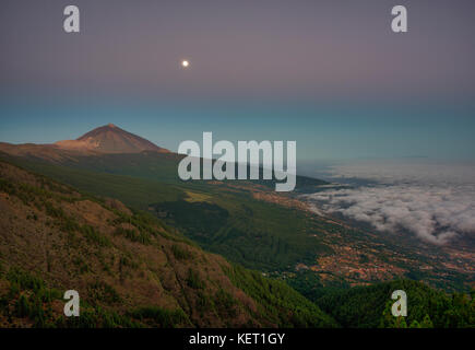 Vue de nuit alizé nuages sur la vallée de la Orotava avec Pico del Teide en face de l'aube, derrière la palma Banque D'Images