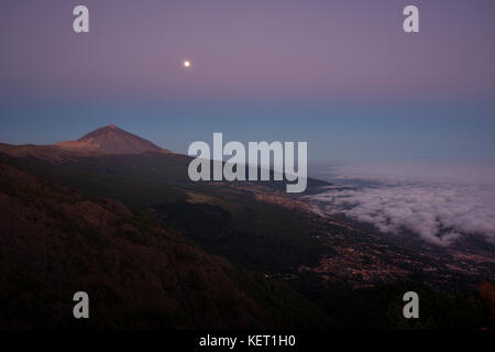 Vue de nuit alizé nuages sur la vallée de la Orotava avec Pico del Teide en face de l'aube, derrière la palma Banque D'Images