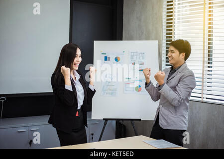 Hommes et de femmes d'affaires et de l'Asie et le succès du concept gagnant - heureuse équipe avec soulevées jusqu'mains célébrant la percée et réalisations Banque D'Images