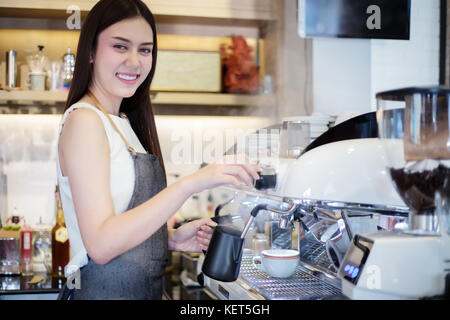 Asian women smiling barista et à l'aide d'une machine à café dans le café au comptoir - femme au travail propriétaire de petite entreprise nourriture et boisson cafe concept Banque D'Images