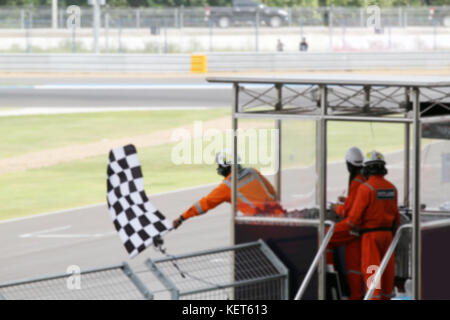 De l'homme flou holdig et agiter le drapeau sur le stand pour la course à la ligne d'arrivée et raceway Banque D'Images