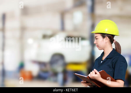 Portrait of smiling young mechanic inspection sur une voiture en atelier de réparation automobile Banque D'Images