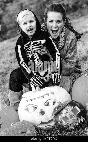 Trick or Treat. jeune mère et fille à l'halloween à l'extérieur parmi les citrouilles jack o'lantern Banque D'Images