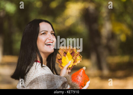 Happy woman outdoors automne. woman holding pumpkin et les feuilles d'automne dans ses mains, Close up, espace blanc Banque D'Images