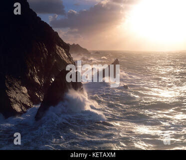 Channel Islands. Guernesey. La Corbiere. Vagues se brisant sur les falaises au lever du soleil. Banque D'Images